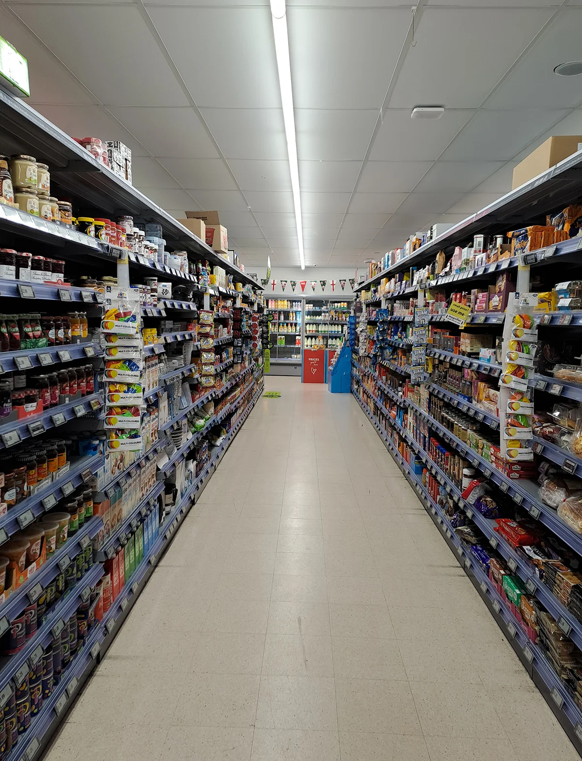 Fully stocked supermarket aisle with grocery shelves on both sides