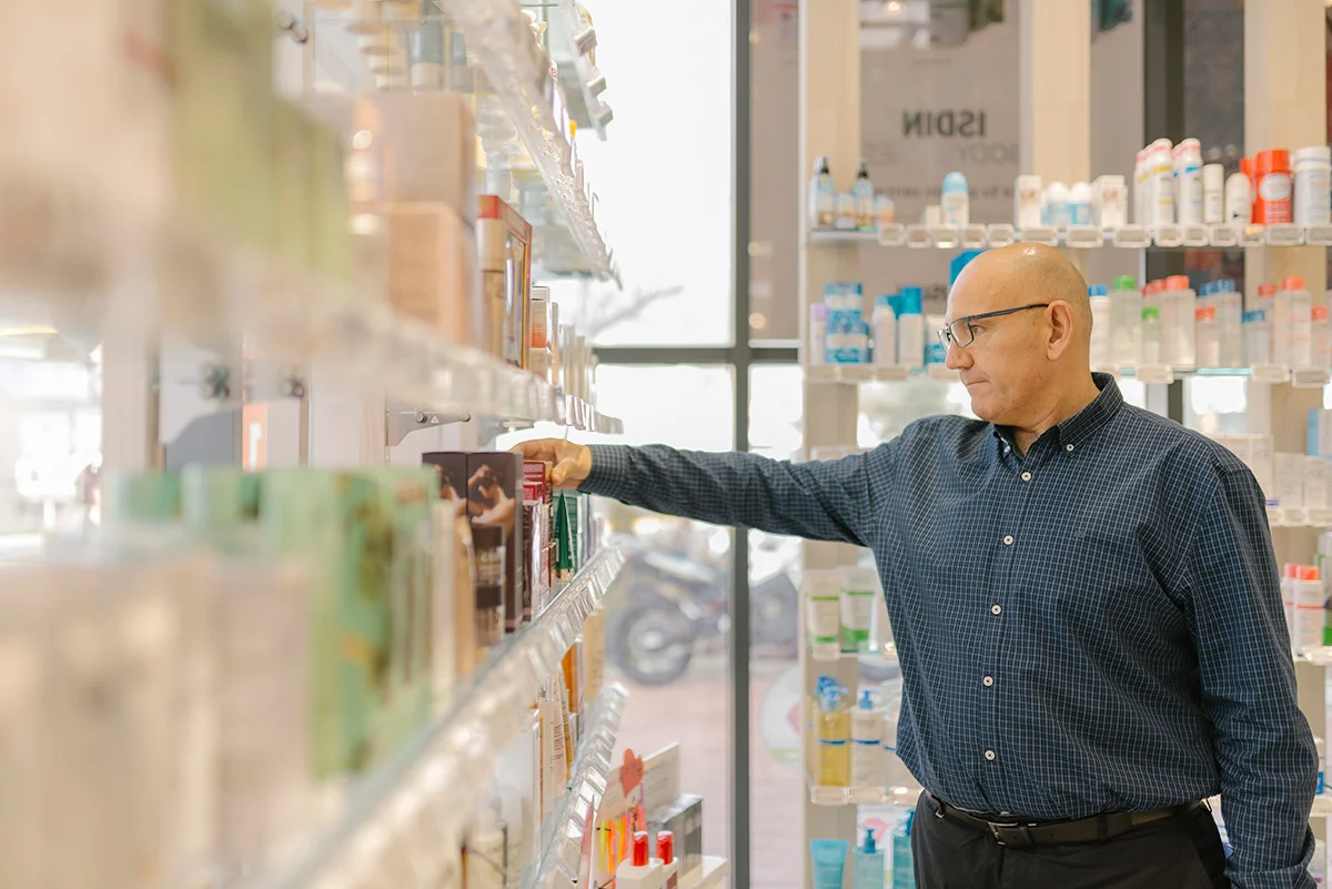 Male customer selecting skincare product from pharmacy shelf in retail store